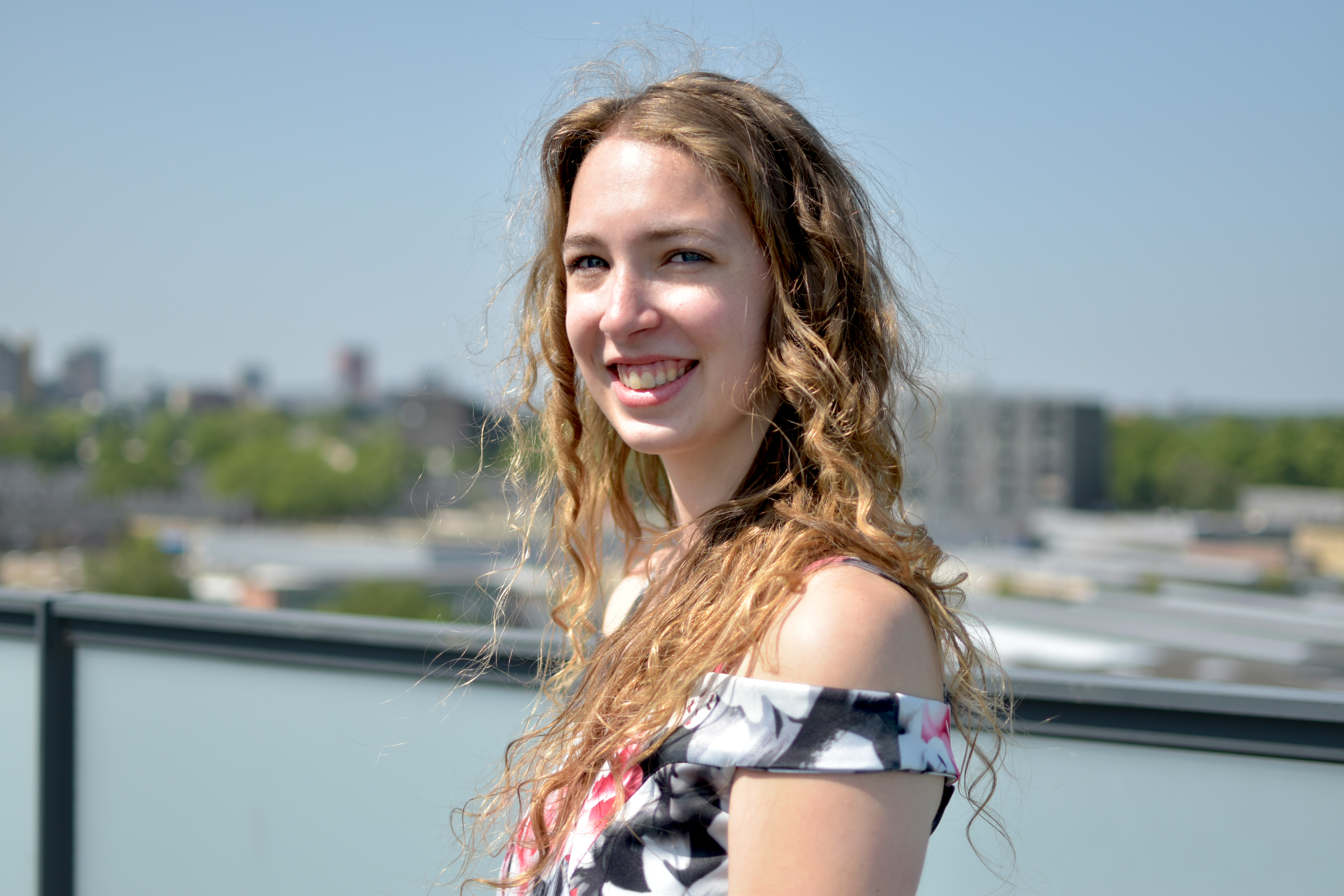 Mara lachend op haar balkon in een zomerjurk