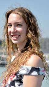 Mara lachend op haar balkon in een zomerjurk