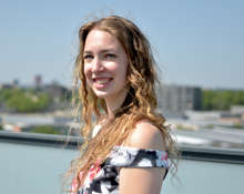 Mara lachend op haar balkon in een zomerjurk