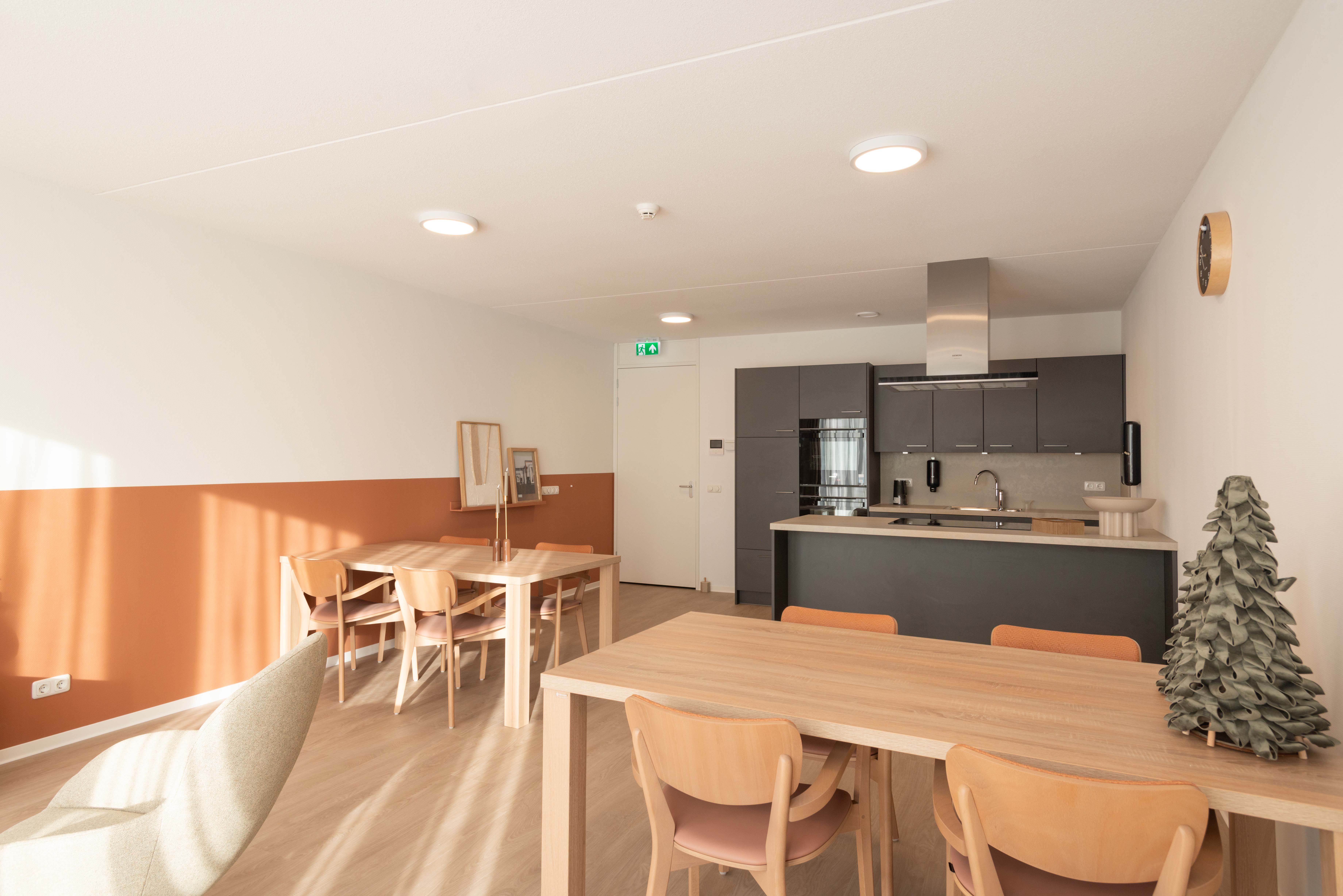 Interieur gemeenschappelijke ruimte Heuvelstraat Dongen met tafels en keukenblok