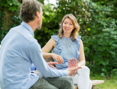 Man en vrouw voeren gesprek op bankje in het park