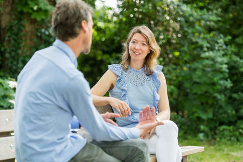 Man en vrouw voeren gesprek op bankje in het park