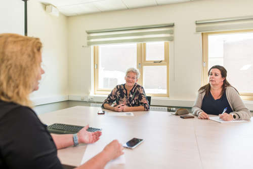 Drie vrouwen in gesprek aan vergadertafel