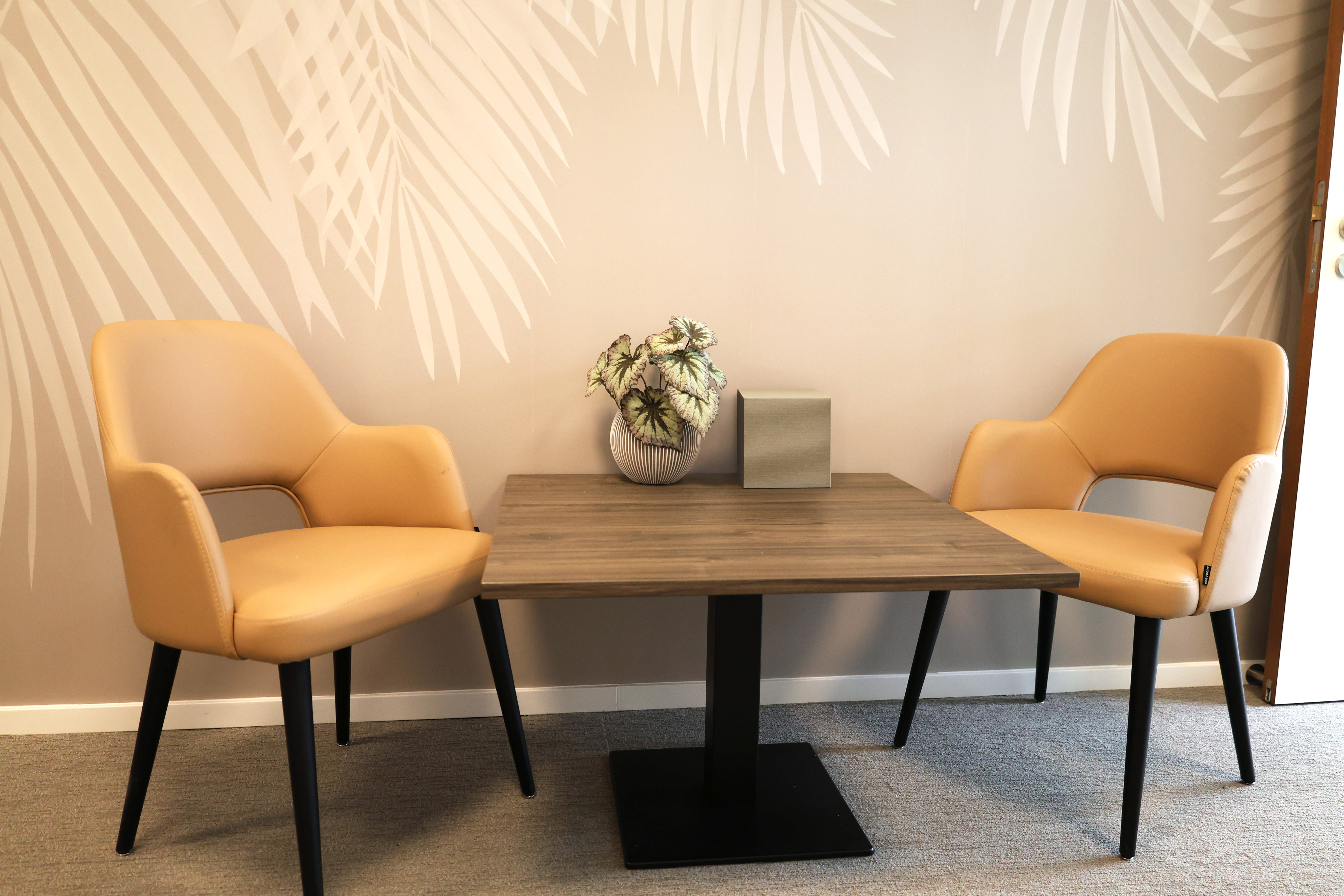 twee lege stoelen aan een tafel in een lege spreekkamer