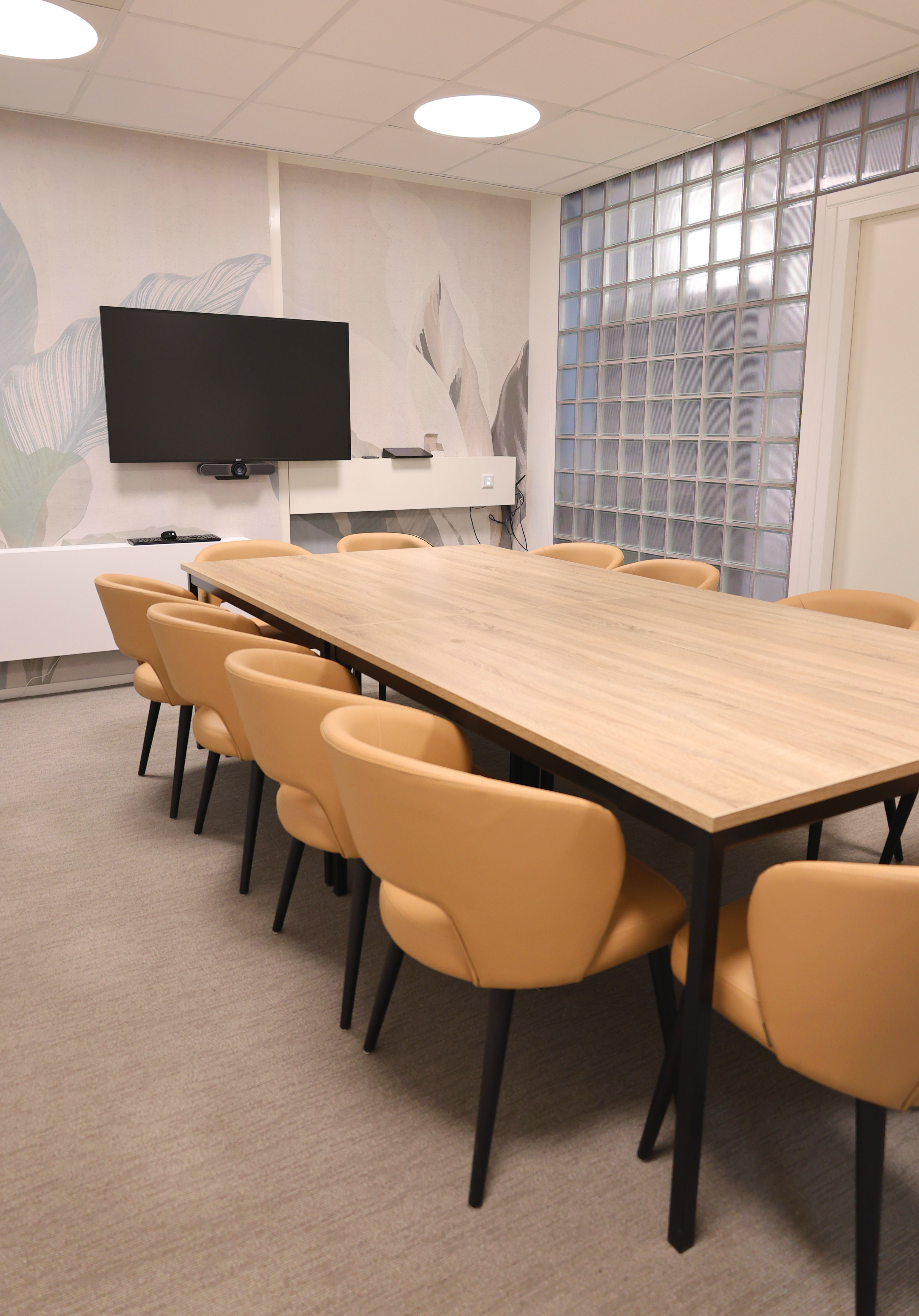 Lichte vergaderruimte met grote tafel en 10 stoelen en groot beeldscherm